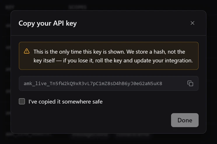 The Copy your API key dialog showing a full amk_live key once, with an I've copied it somewhere safe checkbox