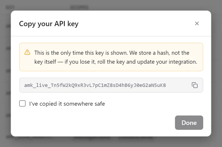 The Copy your API key dialog showing a full amk_live key once, with an I've copied it somewhere safe checkbox